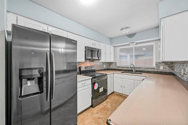 kitchen with white cabinetry, stainless steel appliances, decorative backsplash, sink, and light tile patterned floors