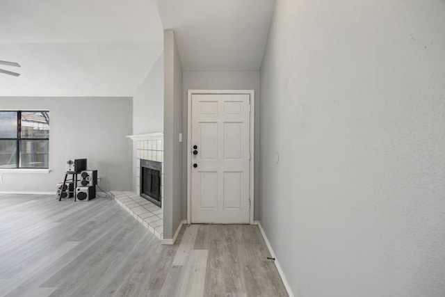 foyer entrance featuring ceiling fan, a fireplace, and light hardwood / wood-style flooring