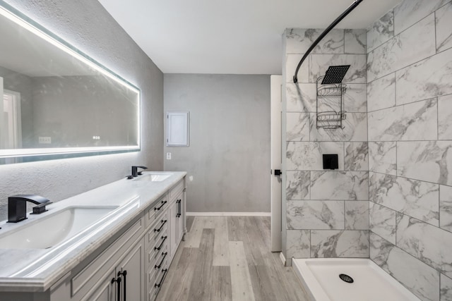 bathroom with hardwood / wood-style floors, vanity, and a tile shower