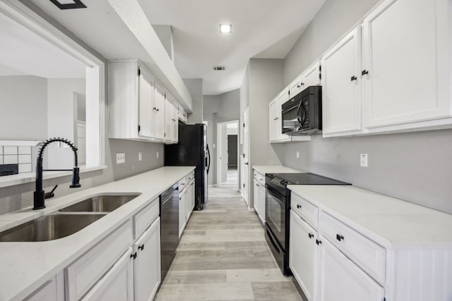 kitchen featuring sink, white cabinetry, black appliances, and light wood-type flooring