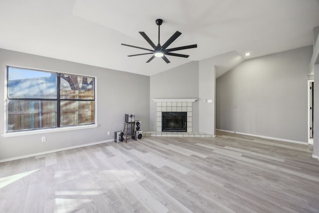 unfurnished living room featuring light hardwood / wood-style floors, a tile fireplace, ceiling fan, and vaulted ceiling