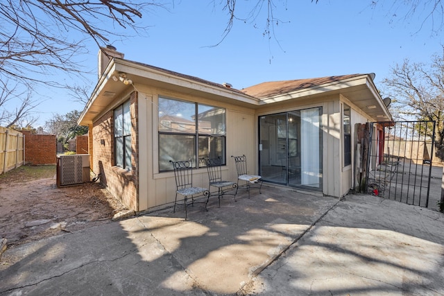 back of property with central AC and a patio