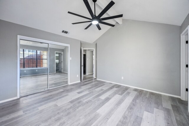 empty room featuring light hardwood / wood-style floors, lofted ceiling with beams, and ceiling fan