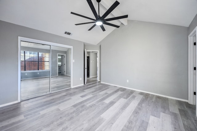 unfurnished bedroom featuring a closet, light wood-type flooring, vaulted ceiling with beams, and ceiling fan