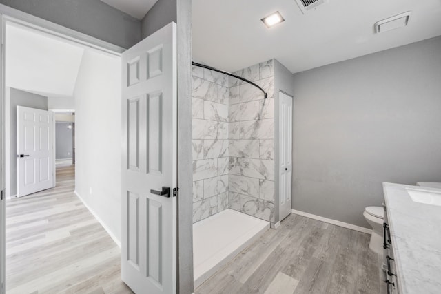 bathroom featuring vanity, toilet, tiled shower, and wood-type flooring