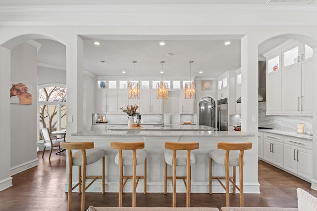 kitchen with an island with sink, white cabinetry, tasteful backsplash, and stainless steel built in refrigerator