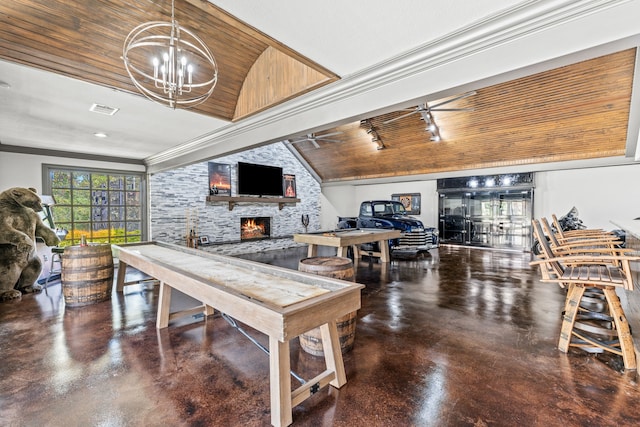 game room featuring ceiling fan with notable chandelier, lofted ceiling, wood ceiling, a stone fireplace, and concrete flooring