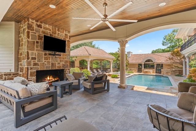 view of patio featuring a gazebo, ceiling fan, and an outdoor living space with a fireplace