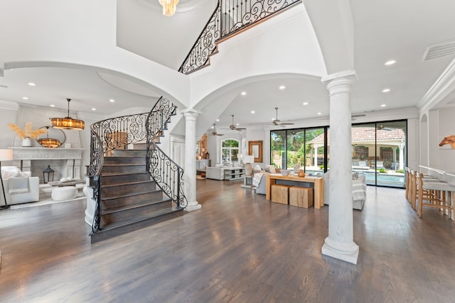 entrance foyer featuring ornamental molding, dark wood-type flooring, ceiling fan, and ornate columns