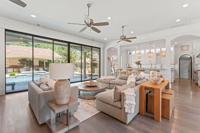 living room featuring ceiling fan, dark hardwood / wood-style flooring, and ornamental molding