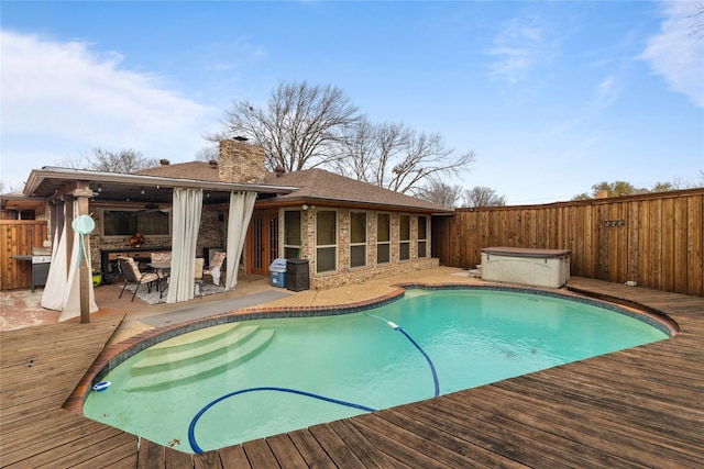 view of pool with a wooden deck, a fenced backyard, ceiling fan, and a hot tub