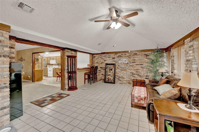 interior space with visible vents, a ceiling fan, a textured ceiling, light tile patterned flooring, and vaulted ceiling