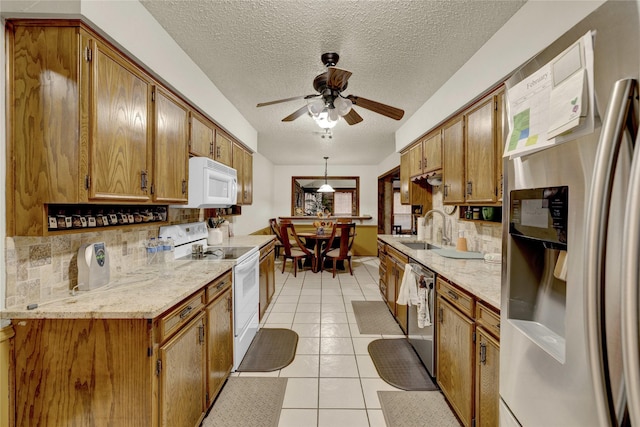 kitchen with light tile patterned floors, decorative backsplash, appliances with stainless steel finishes, brown cabinetry, and a sink