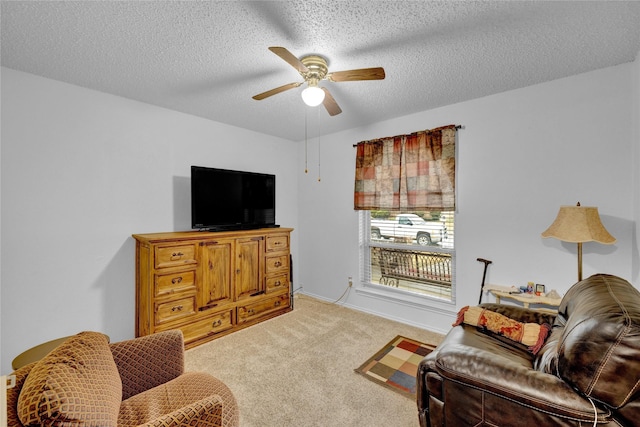 living area with light colored carpet, a textured ceiling, and ceiling fan