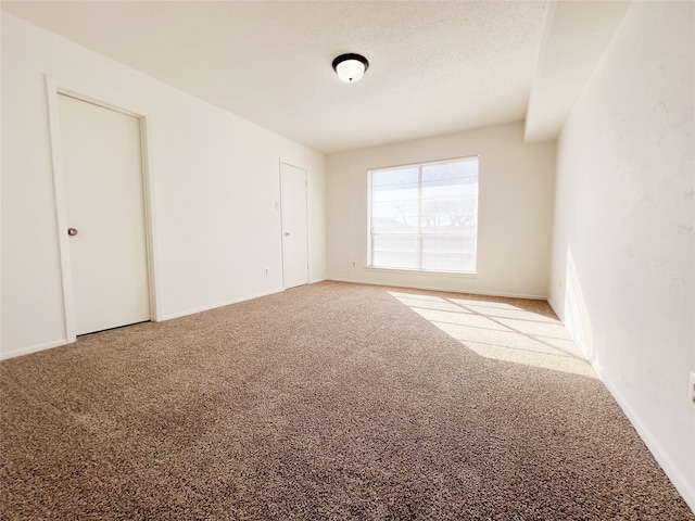 spare room featuring a textured ceiling and carpet