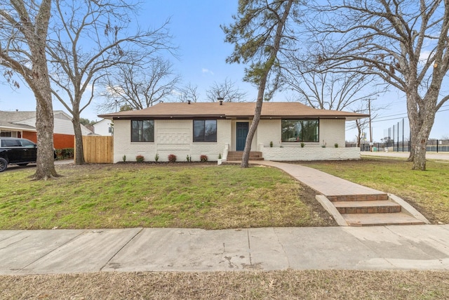 ranch-style home with a front yard, brick siding, and fence