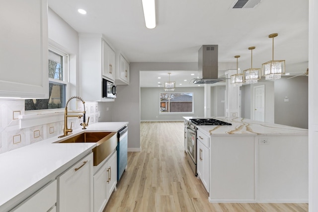 kitchen featuring white cabinets, stainless steel appliances, decorative light fixtures, and island range hood