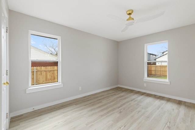 spare room featuring ceiling fan, a wealth of natural light, and light hardwood / wood-style flooring