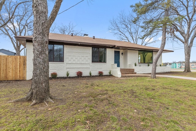 ranch-style home featuring fence, a front lawn, and brick siding