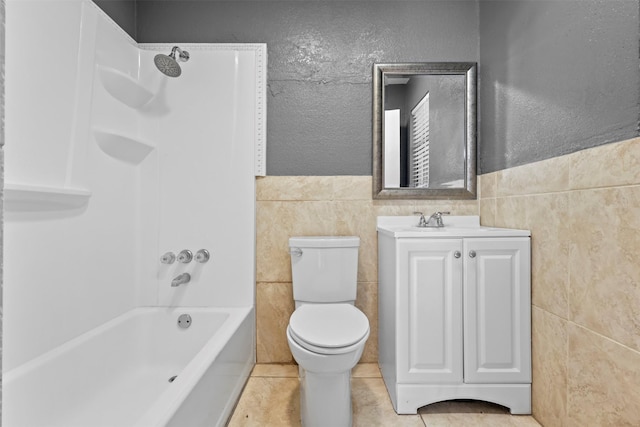 full bathroom featuring tile patterned floors, toilet, bathtub / shower combination, tile walls, and vanity