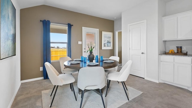 dining area with vaulted ceiling and light tile patterned floors