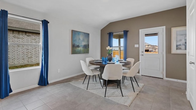 tiled dining room featuring lofted ceiling