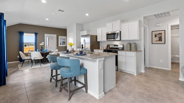 kitchen featuring white cabinetry, stainless steel appliances, a kitchen breakfast bar, a kitchen island with sink, and light tile patterned flooring