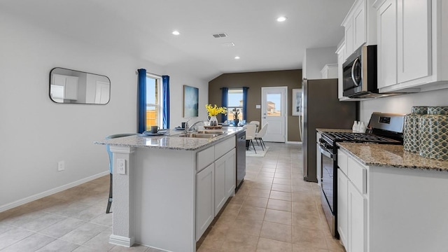 kitchen featuring appliances with stainless steel finishes, white cabinets, sink, a center island with sink, and lofted ceiling