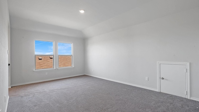 spare room featuring carpet flooring and vaulted ceiling