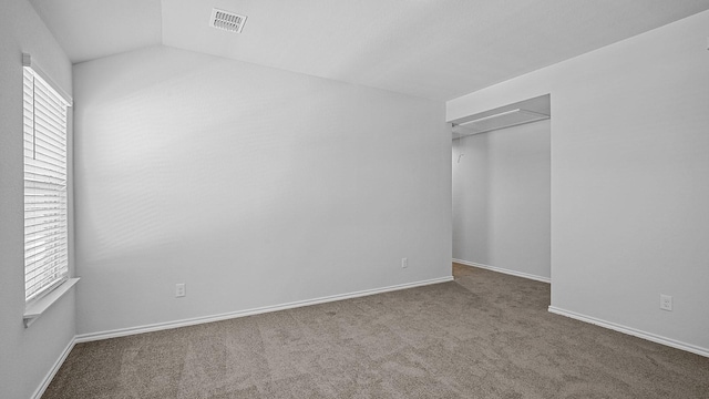 spare room with carpet flooring and lofted ceiling