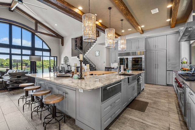 kitchen with decorative light fixtures, gray cabinetry, light stone countertops, and a spacious island