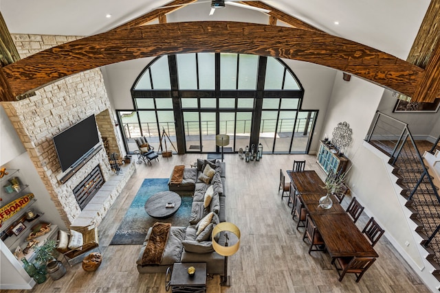 living room featuring a fireplace, hardwood / wood-style flooring, beamed ceiling, and a healthy amount of sunlight