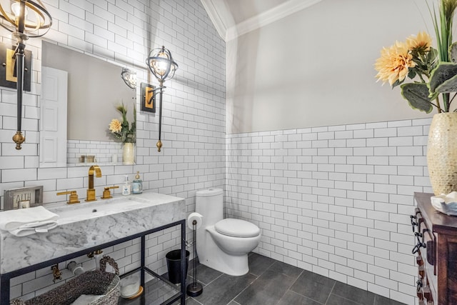 bathroom featuring toilet, crown molding, tile walls, sink, and lofted ceiling