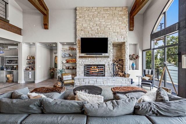 living room with a high ceiling, wood-type flooring, beam ceiling, and a stone fireplace