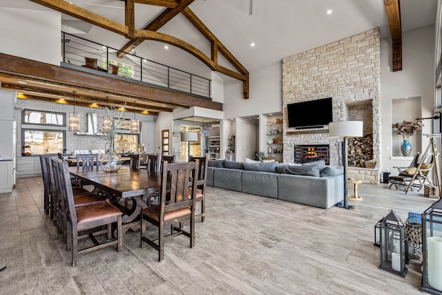 dining area with high vaulted ceiling, beamed ceiling, and a stone fireplace