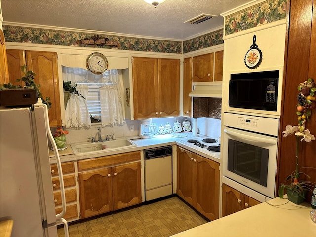 kitchen with sink, white appliances, and a textured ceiling