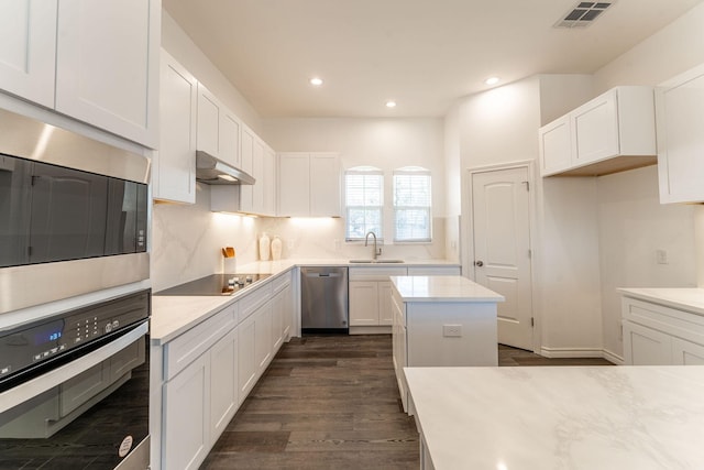 kitchen featuring appliances with stainless steel finishes, white cabinetry, sink, a kitchen island, and dark hardwood / wood-style floors