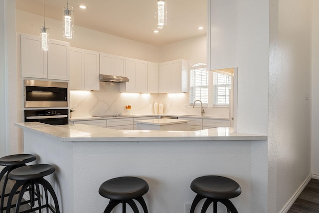 kitchen featuring black appliances, white cabinetry, sink, and a breakfast bar