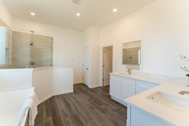 bathroom featuring wood-type flooring, tiled shower, and vanity