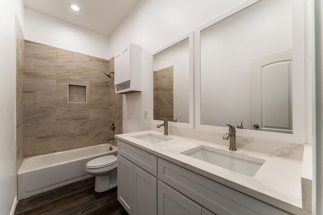 full bathroom with hardwood / wood-style floors, toilet, vanity, and tiled shower / bath