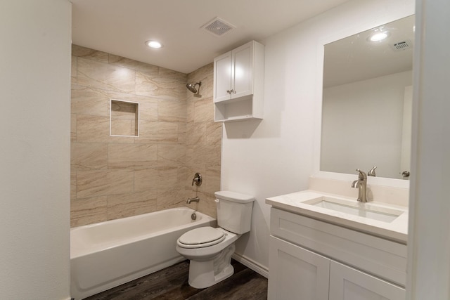 full bathroom featuring hardwood / wood-style flooring, tiled shower / bath combo, vanity, and toilet