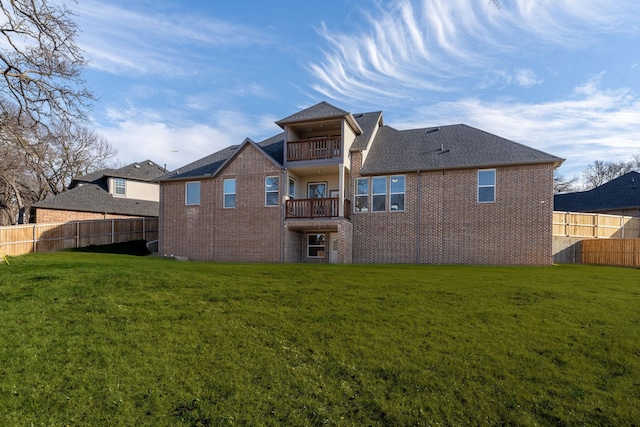 rear view of property with a balcony and a lawn