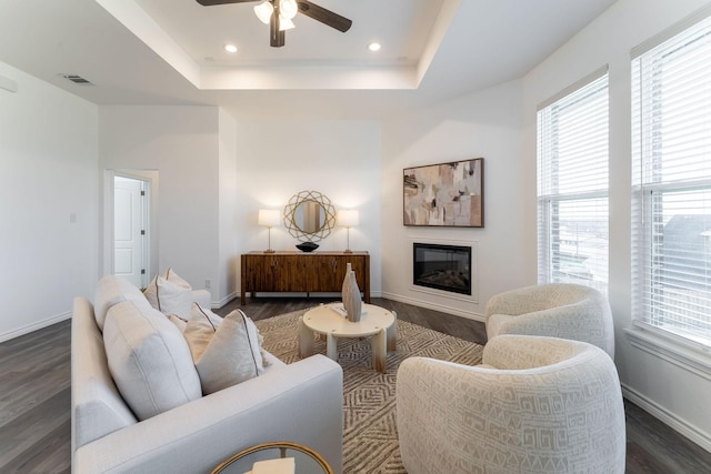 living room featuring dark hardwood / wood-style floors, ceiling fan, and a raised ceiling