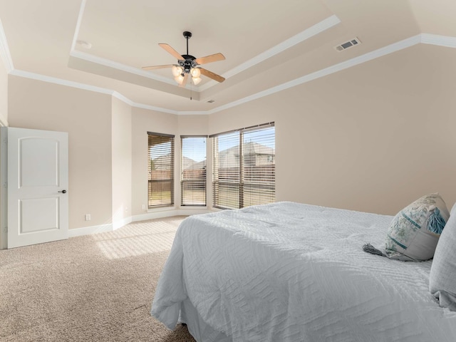 carpeted bedroom with ceiling fan, ornamental molding, and a tray ceiling