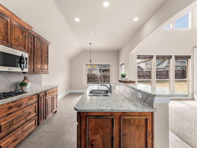 kitchen with sink, a center island with sink, vaulted ceiling, and appliances with stainless steel finishes