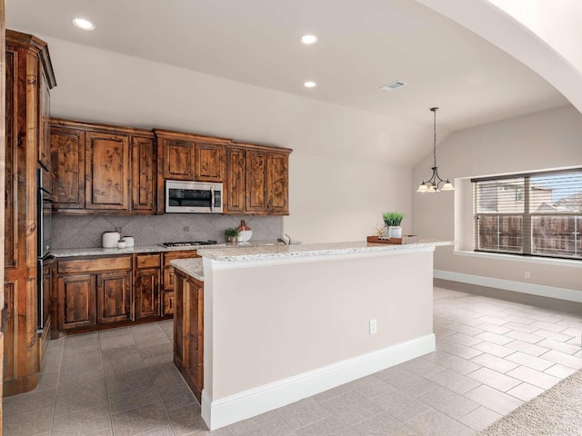 kitchen featuring pendant lighting, light tile patterned floors, appliances with stainless steel finishes, decorative backsplash, and vaulted ceiling