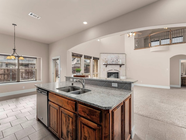 kitchen with light tile patterned flooring, sink, stainless steel dishwasher, and decorative light fixtures