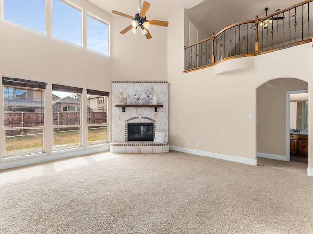 unfurnished living room featuring a towering ceiling, a healthy amount of sunlight, and carpet