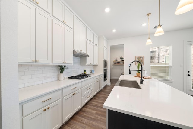 kitchen featuring appliances with stainless steel finishes, white cabinetry, a kitchen island with sink, sink, and pendant lighting