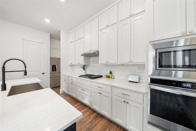 kitchen with tasteful backsplash, white cabinetry, sink, stainless steel appliances, and dark hardwood / wood-style floors